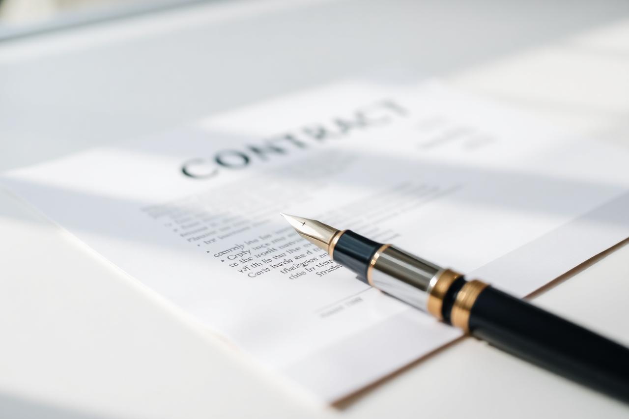 Printed contract document with a pen resting on the signature page